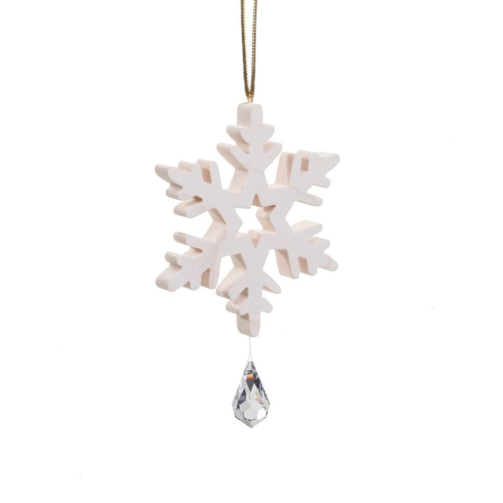 A white wooden snowflake Christmas ornament with a clear faceted crystal teardrop hanging from the center, suspended by a thin gold string against a plain white background.